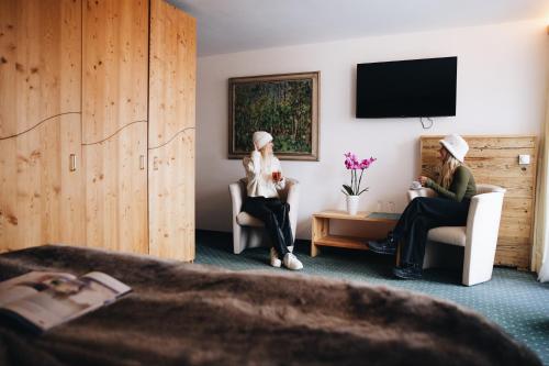 Due donne sedute sulle sedie in una camera d'albergo di Hotel Grischuna a Bivio