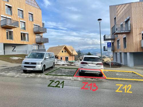 two cars parked in a parking lot next to buildings at KUBÍNSKA HOĽA - Apartmány HILLSIDE point in Dolný Kubín