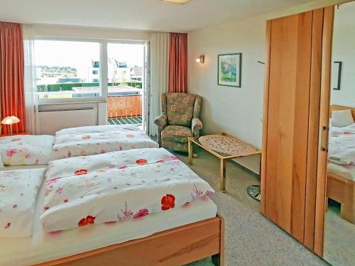 ein Hotelzimmer mit 2 Betten und einem Stuhl in der Unterkunft Haus Kees - Wohnung 1 in Kressbronn am Bodensee