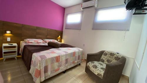 een slaapkamer met een bed en een stoel bij Cantinho do sossego in Blumenau