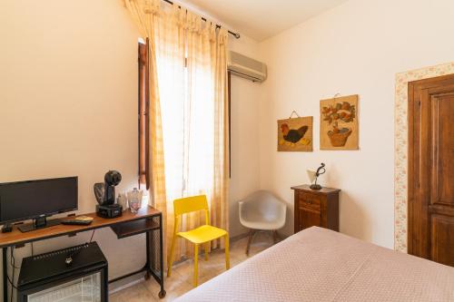 a bedroom with a bed and a desk with a television at Agriturismo Il Giglio in Oristano