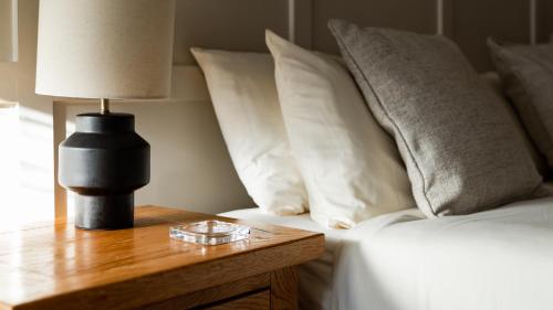 a bed with white pillows and a table with a lamp at The Waterfront in Anstruther