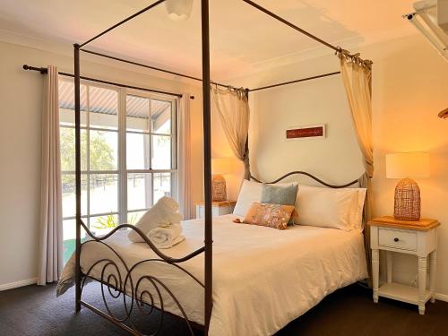 a bedroom with a four poster bed and a window at Cadair Cottages in Rosebrook