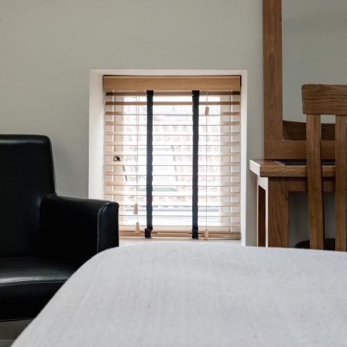 a room with a bed and two chairs and a window at The Waterfront in Anstruther