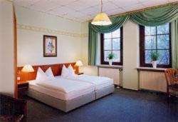 a bedroom with a large white bed and two windows at Deckert's Hotel & Restaurant in Lutherstadt Eisleben