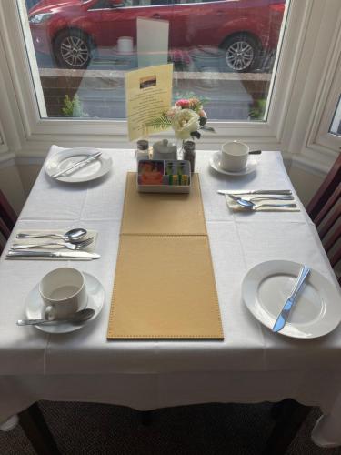 a white table with plates and utensils on it at Ellies Guest House in Whitby