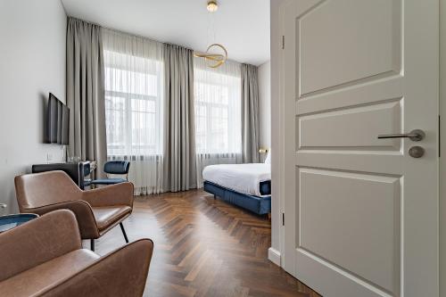 a hotel room with a bed and chairs and a door at GRAND CROWN in Vilnius