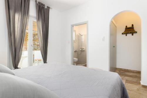 a white bedroom with a large bed and a bathroom at Roses Beach in Parikia