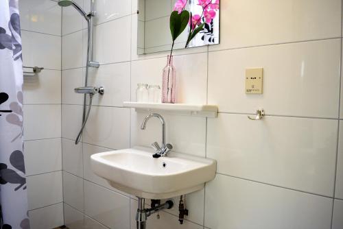 a white bathroom with a sink and a mirror at ALO43 renovated holiday home in Aagtekerke