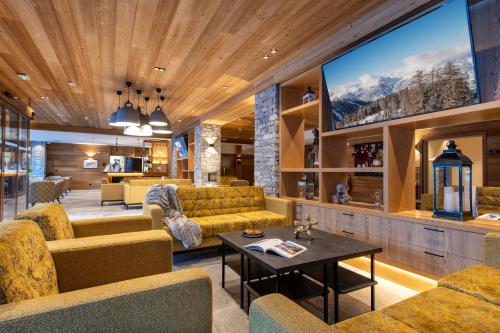 Una sala de estar con sofás y un televisor. en CGH Résidences & Spas White Pearl Lodge, en La Plagne