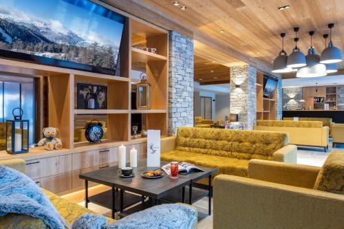 Una sala de estar con sofás y un televisor. en CGH Résidences & Spas White Pearl Lodge, en La Plagne