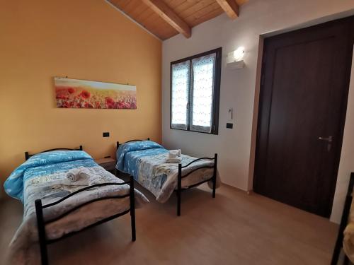 2 camas en una habitación con puerta y ventana en B&B LA DEA LUMACA, en Villareggia