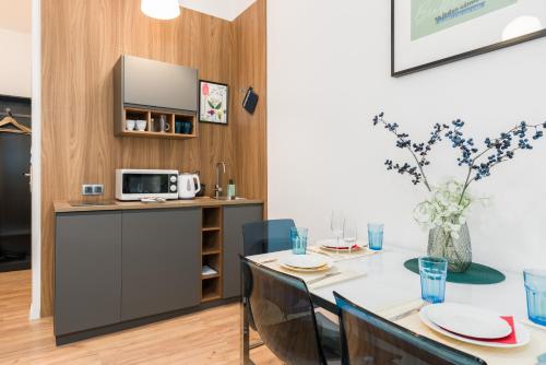 a kitchen and dining room with a table and a microwave at Kwiatowa Apartments Poznań City Center by Renters in Poznań