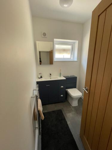 uma casa de banho com um lavatório, um WC e uma janela. em The Hideaway em Modbury
