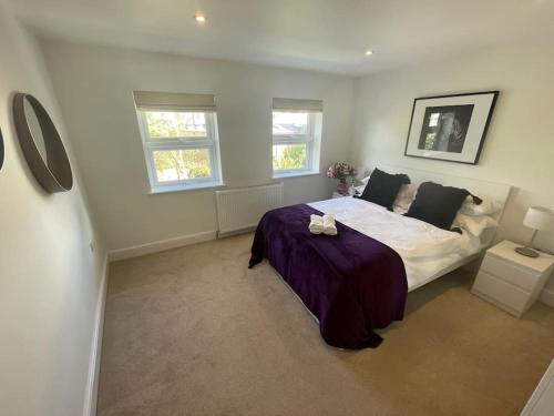 a bedroom with a large bed and two windows at Light and Modern 2BR 1.5BA, newly refurbished! in Raynes Park