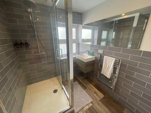 La salle de bains est pourvue d'une douche, d'un lavabo et d'un miroir. dans l'établissement Light and Modern 2BR 1.5BA, newly refurbished!, à Raynes Park