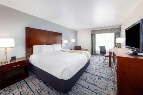 a hotel room with a bed and a flat screen tv at La Quinta Inn by Wyndham Lynnwood in Lynnwood