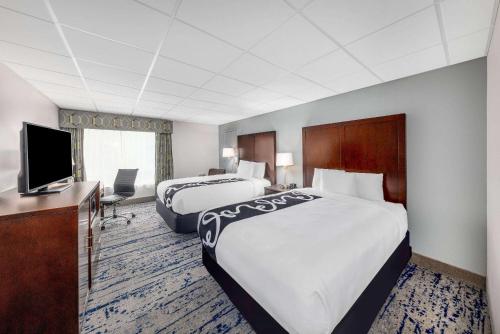 a hotel room with two beds and a television at La Quinta Inn by Wyndham Lynnwood in Lynnwood