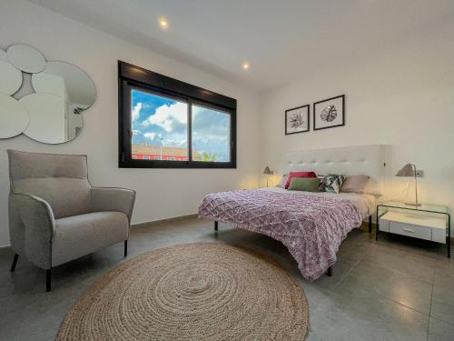 a bedroom with a bed and a chair and a window at Villamar 15B - Ático con solárium cerca de las salinas in San Pedro del Pinatar