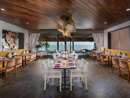 une salle à manger avec une grande table et des chaises dans l'établissement The Bheemli Resort Managed by AccorHotels, à Visakhapatnam