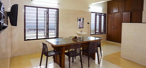 a kitchen with a table and chairs and a refrigerator at Rosan Heritage - A Beach Villa in Kanyakumari