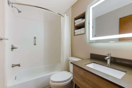 een badkamer met een wastafel, een toilet en een spiegel bij Econo Lodge Inn & Suites on the River in Gatlinburg