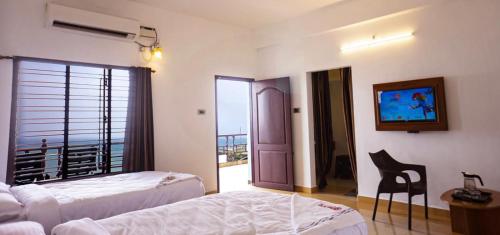 a hotel room with two beds and a balcony at Rosan Heritage - A Beach Villa in Kanyakumari