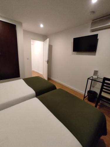 a bedroom with two beds and a flat screen tv at Residencial Douro in Peso da Régua