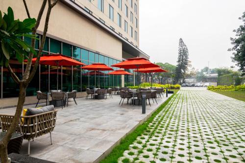 a patio with tables and chairs and red umbrellas at Holiday Inn Express Kolkata Airport by IHG in Kolkata