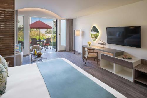 a hotel room with a bed and a desk and a television at JA Palm Tree Court, Dubai in Dubai