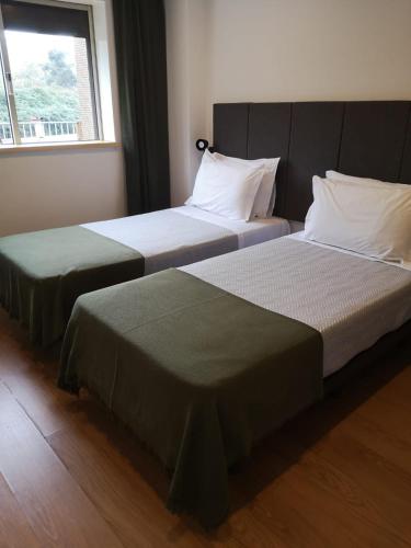 two beds sitting next to each other in a room at Residencial Douro in Peso da Régua