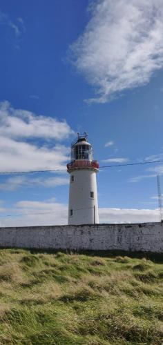 a white lighthouse sitting on top of a wall at Cois na Mara Eire code V15 T677 in Bridge of Ross