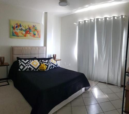 sypialnia z czarnym łóżkiem i białymi zasłonami w obiekcie Hermoso departamento en Bombas con vista al mar w mieście Bombinhas