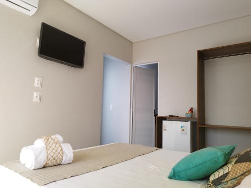 a bedroom with a bed with a flat screen tv on the wall at Bless in Maragogi