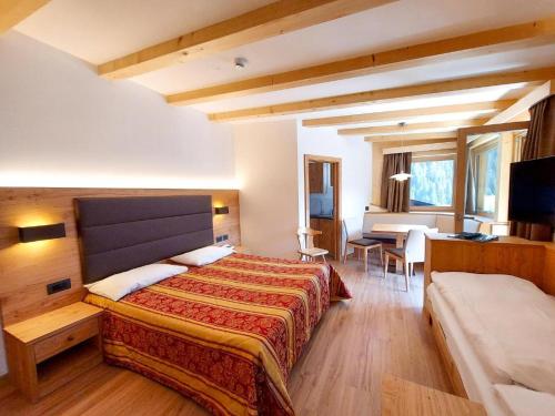 a bedroom with a bed and a desk and a table at Albergo Arnica in Canazei