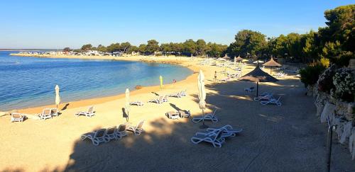 a beach with chairs and umbrellas and the ocean at Mobilna kućica Nika in Šimuni