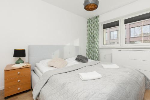 a white bedroom with a large bed and a window at Ochota Spacious Apartment with Parking by Renters in Warsaw