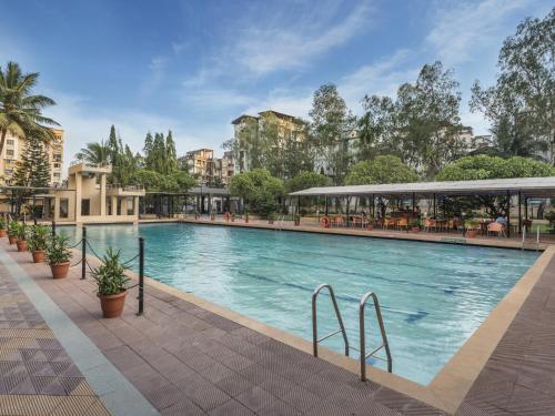 a large swimming pool in a city with buildings at GCC Hotel and Club in Mumbai