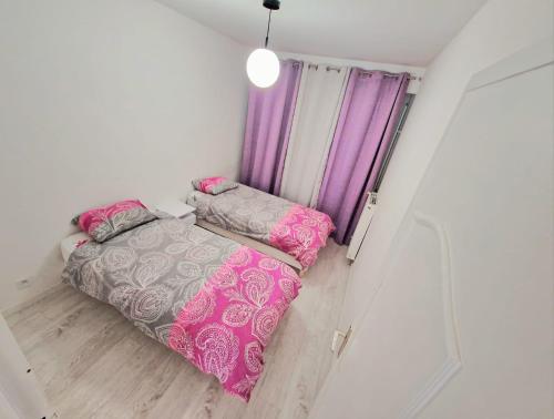 Cette petite chambre comprend 2 lits et des rideaux violets. dans l'établissement Grand Appartement Meublé - Cosyrenty Créteil, à Créteil