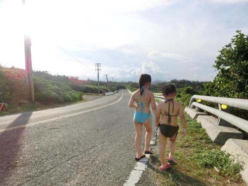 two girls in bathing suits walking down a road at Sea Shore Hotel in Manzhou