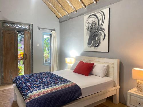 una camera da letto con un letto con cuscini rossi e una finestra di Pranajaya Loka a Tejakula