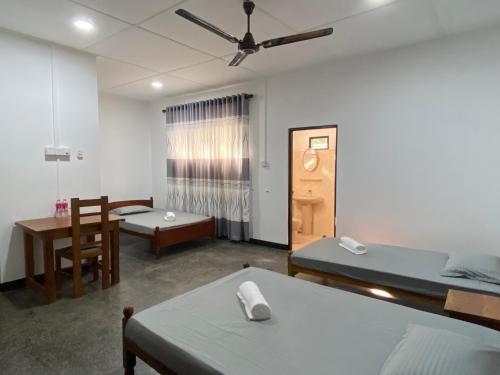 a room with two beds and a table and chairs at Berty's Cottage in Jaffna