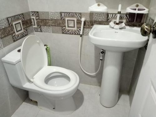 uma casa de banho com um WC branco e um lavatório. em Johar Hill view Guest House em Carachi