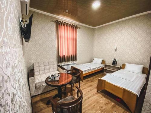 a room with two beds and a table in it at Polvon Ota Hotel in Khiva