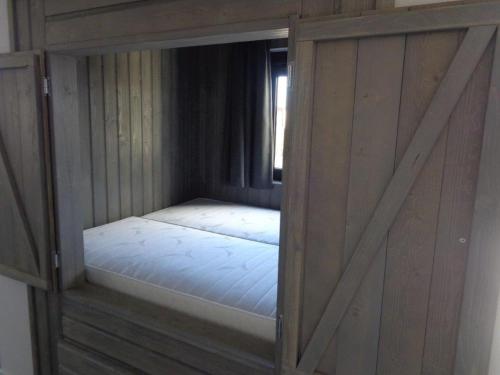 a small bed in a wooden room with a window at Recreatiepark Jachthaven De Veerstal Lathum - Luxe Chalet in Lathum