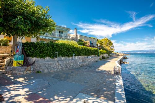 a sidewalk next to the water in front of a building at Apartments Dinka Vantačići in Malinska