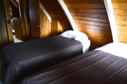 deux lits dans une chambre aux murs en bois dans l'établissement Cozy Cabin at RED - Steps to Skiing & Trails, à Rossland