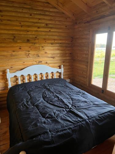 a bedroom with a bed in a log cabin at Cabañas Puesta del Sol in Las Flores