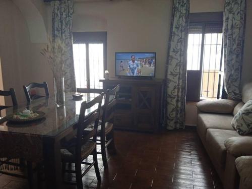 salon ze stołem jadalnym i telewizorem w obiekcie La casa de la cuevecita w mieście Arcos de la Frontera