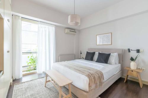 een witte slaapkamer met een groot bed en een raam bij Panoramic 1BR Apartment near Kallimarmaro Stadium by UPSTREET in Athene